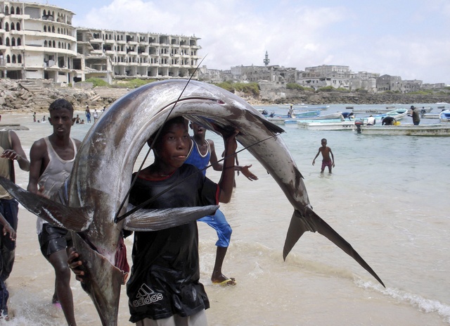 A Somalia young man carries a fish on his head near the shores of Indian ocean in Mogadishu